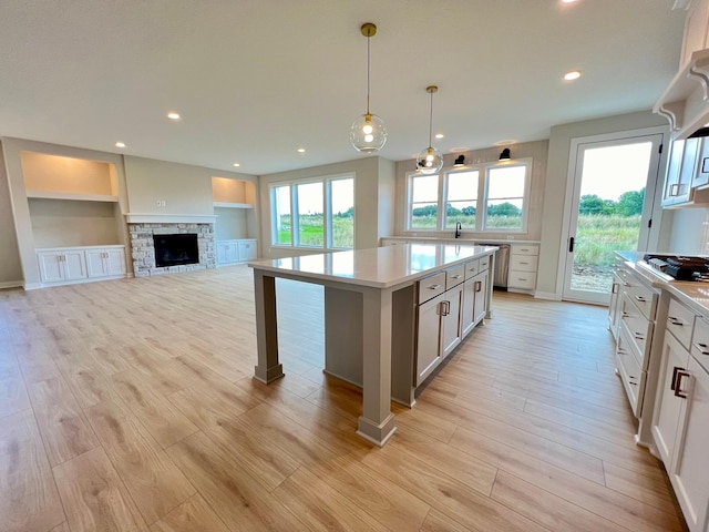 kitchen featuring white cabinetry, decorative light fixtures, light hardwood / wood-style floors, and a center island