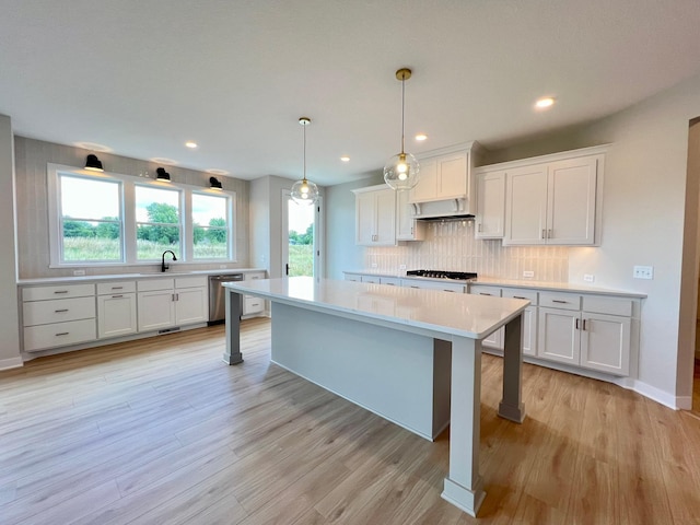 kitchen with stainless steel dishwasher, white cabinets, a kitchen breakfast bar, and decorative light fixtures