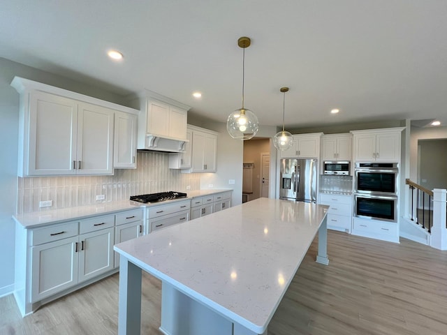 kitchen with decorative light fixtures, a center island, appliances with stainless steel finishes, white cabinets, and backsplash