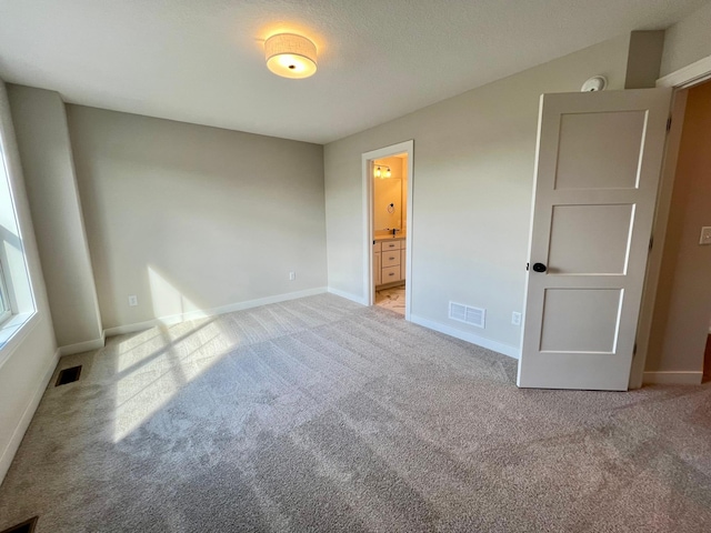 unfurnished bedroom with light carpet and ensuite bath