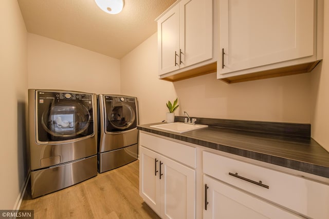 laundry area featuring cabinets, sink, independent washer and dryer, and light wood-type flooring