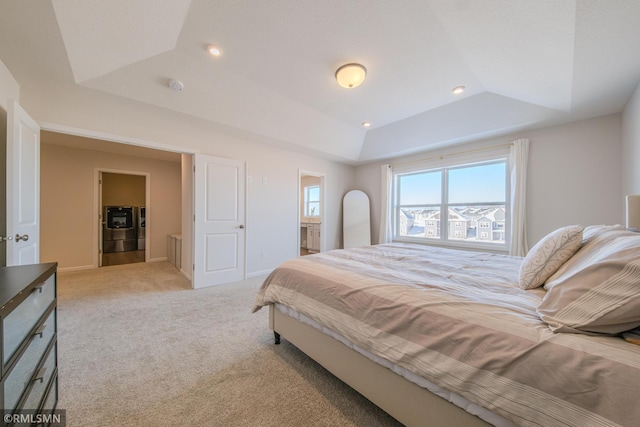 carpeted bedroom featuring a raised ceiling, connected bathroom, and washing machine and clothes dryer