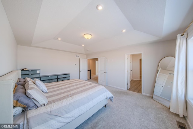 bedroom with a raised ceiling and light colored carpet