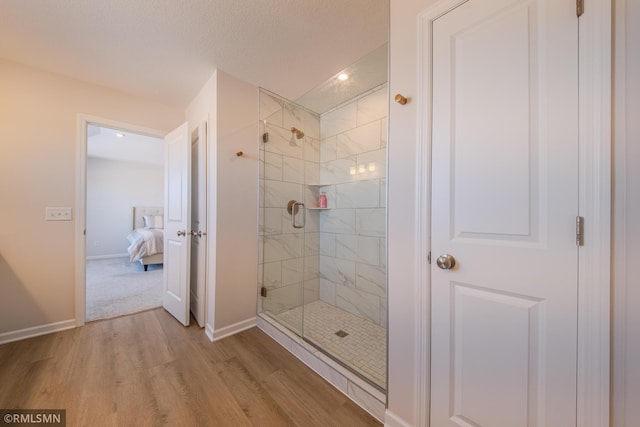 bathroom with wood-type flooring, a textured ceiling, and a shower with shower door