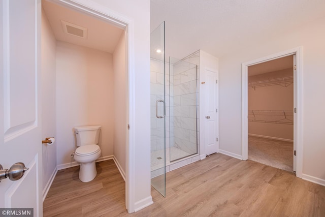 bathroom featuring hardwood / wood-style flooring, an enclosed shower, and toilet