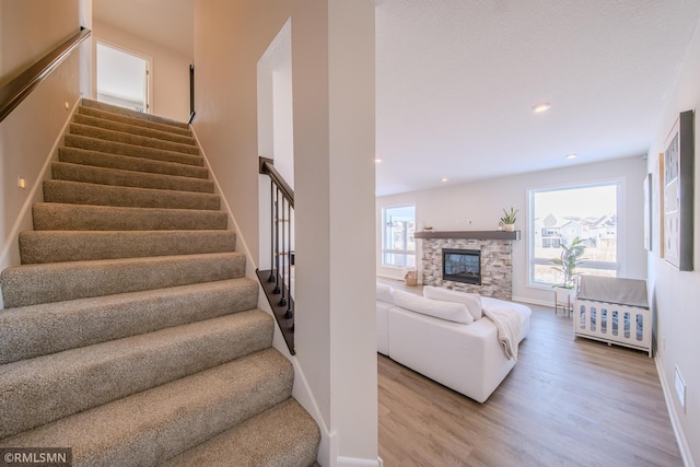 stairs with hardwood / wood-style floors and a stone fireplace