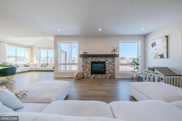 living room featuring lofted ceiling, a stone fireplace, hardwood / wood-style floors, and a wealth of natural light