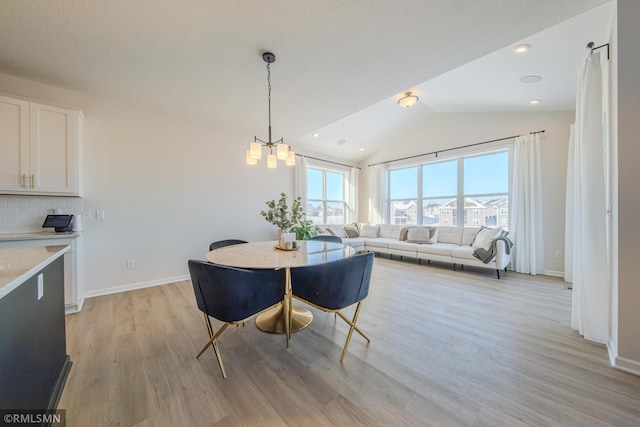 dining area featuring light hardwood / wood-style flooring, a notable chandelier, and vaulted ceiling