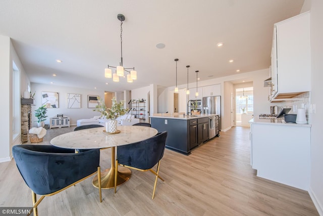 dining area featuring sink, an inviting chandelier, and light hardwood / wood-style floors