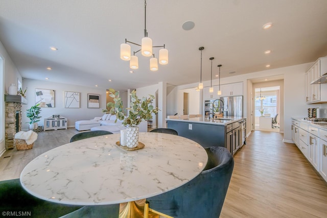 dining space with an inviting chandelier, sink, a fireplace, and light wood-type flooring