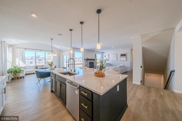 kitchen with a center island with sink, sink, stainless steel dishwasher, and decorative light fixtures