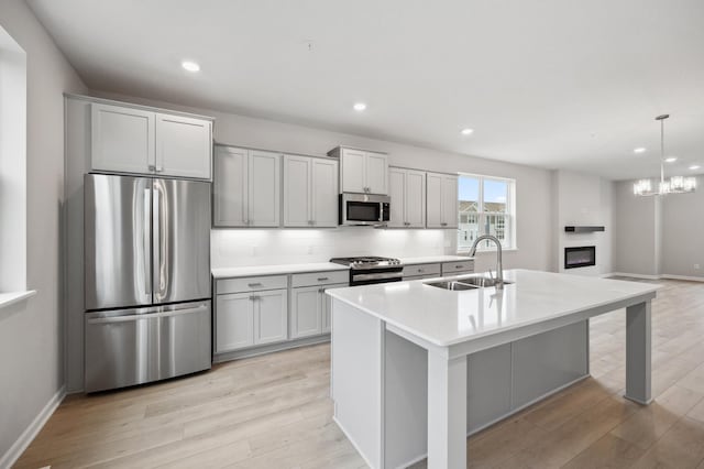 kitchen featuring an island with sink, appliances with stainless steel finishes, light hardwood / wood-style floors, and sink