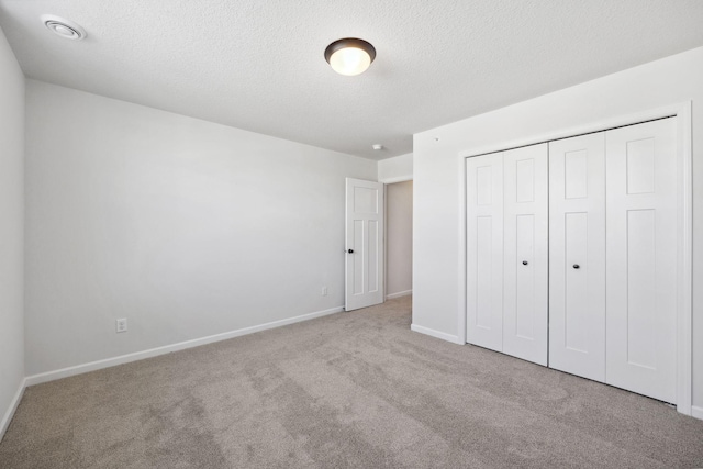 unfurnished bedroom featuring a closet, light carpet, and a textured ceiling