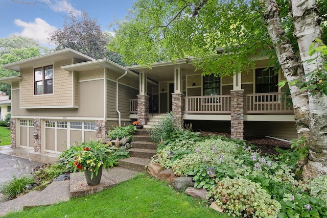 view of front of house with a garage, covered porch, stone siding, and driveway