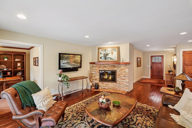 living room featuring a stone fireplace, recessed lighting, baseboards, and hardwood / wood-style floors