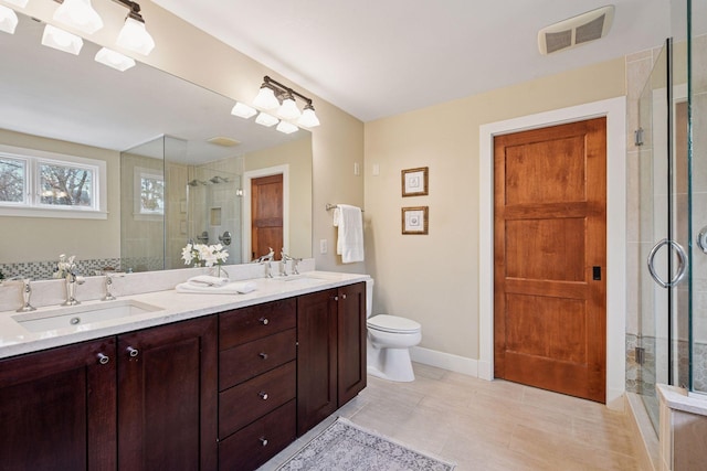 bathroom featuring baseboards, visible vents, double vanity, a stall shower, and a sink