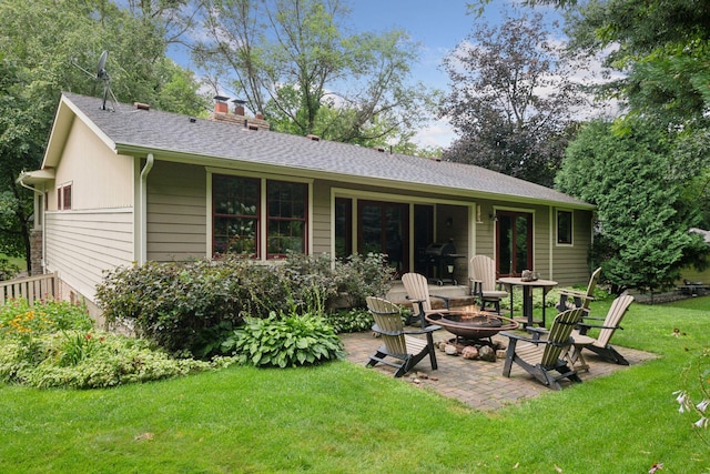 back of property featuring a lawn, a patio, a fire pit, roof with shingles, and a chimney