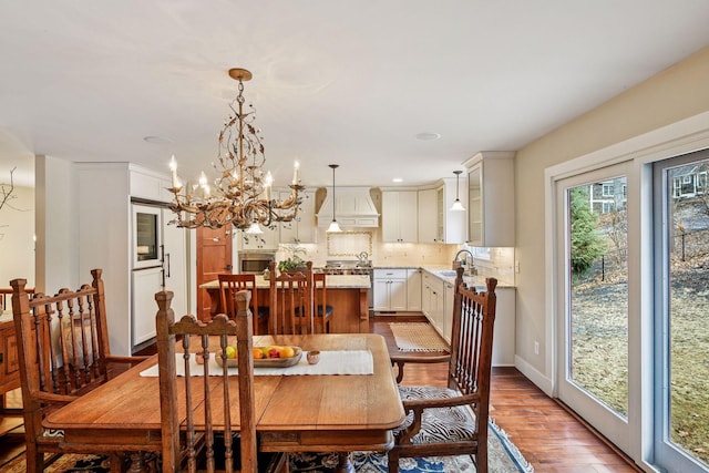 dining room with wood finished floors, a chandelier, recessed lighting, and baseboards