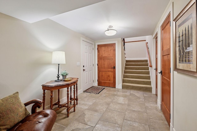 foyer entrance with stairs and baseboards
