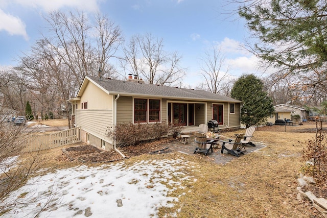 rear view of house featuring an outdoor fire pit, fence, and a chimney