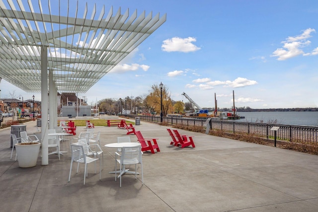 view of patio with fence, a pergola, and a water view