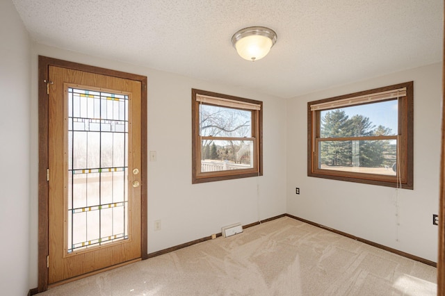 interior space featuring light colored carpet and a textured ceiling