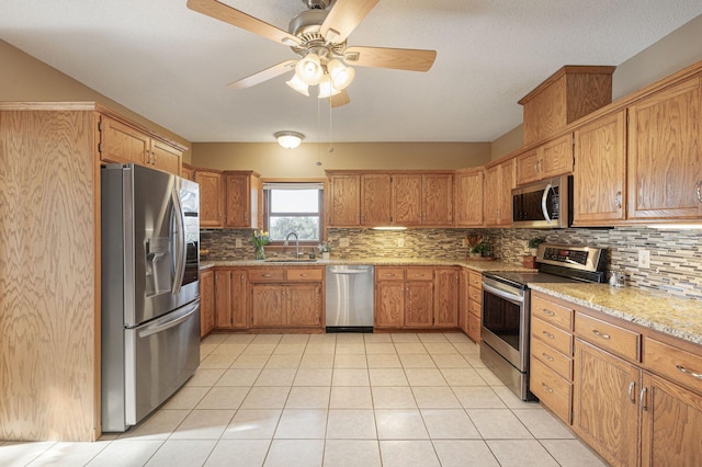 kitchen featuring tasteful backsplash, sink, light tile patterned floors, light stone counters, and stainless steel appliances