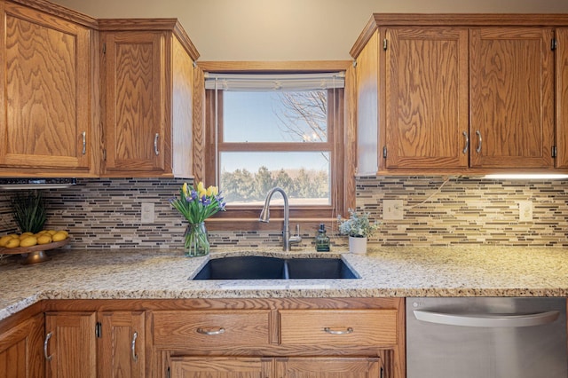 kitchen featuring sink, stainless steel dishwasher, light stone counters, and decorative backsplash