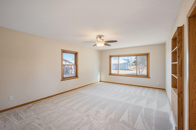 carpeted spare room featuring ceiling fan and a textured ceiling