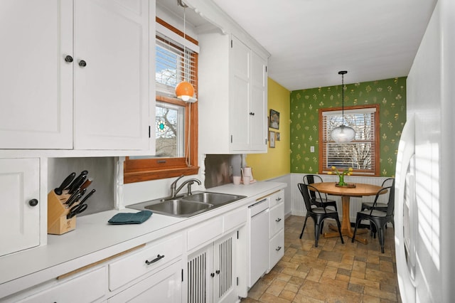 kitchen featuring white cabinetry, sink, pendant lighting, and white appliances