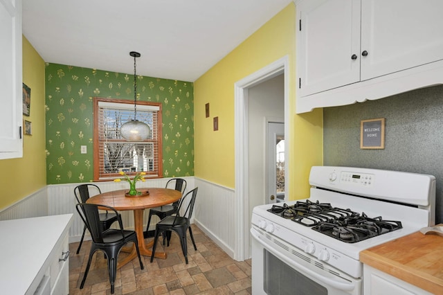 kitchen featuring white cabinetry, decorative light fixtures, and gas range gas stove