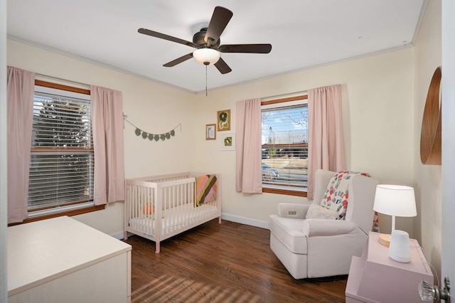 bedroom with a nursery area, ceiling fan, dark hardwood / wood-style flooring, and crown molding