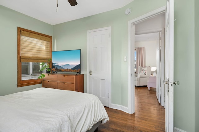 bedroom with multiple windows, dark hardwood / wood-style floors, and ceiling fan