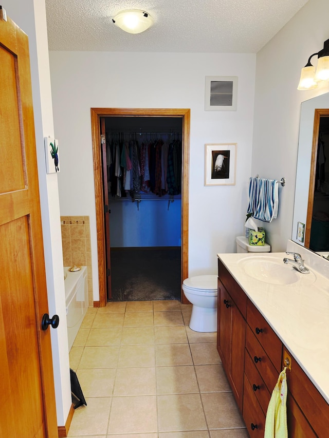 bathroom featuring toilet, a textured ceiling, vanity, a tub, and tile patterned flooring