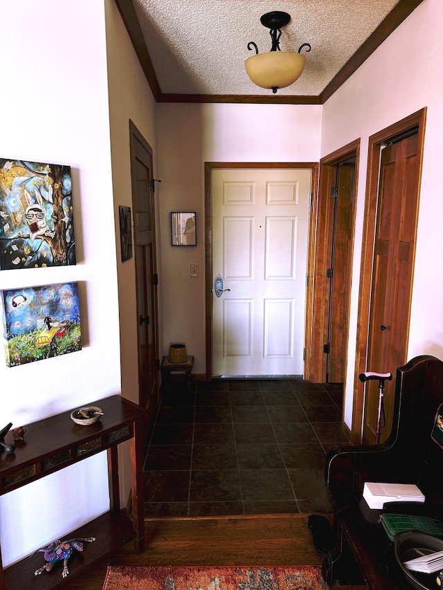 entrance foyer with crown molding, a textured ceiling, and dark tile patterned floors