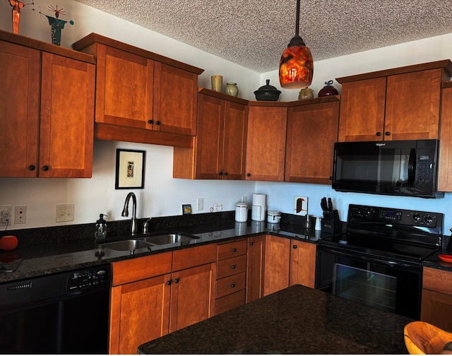 kitchen featuring sink, hanging light fixtures, a textured ceiling, dark stone counters, and black appliances