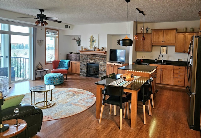 kitchen featuring pendant lighting, dark countertops, freestanding refrigerator, open floor plan, and a sink