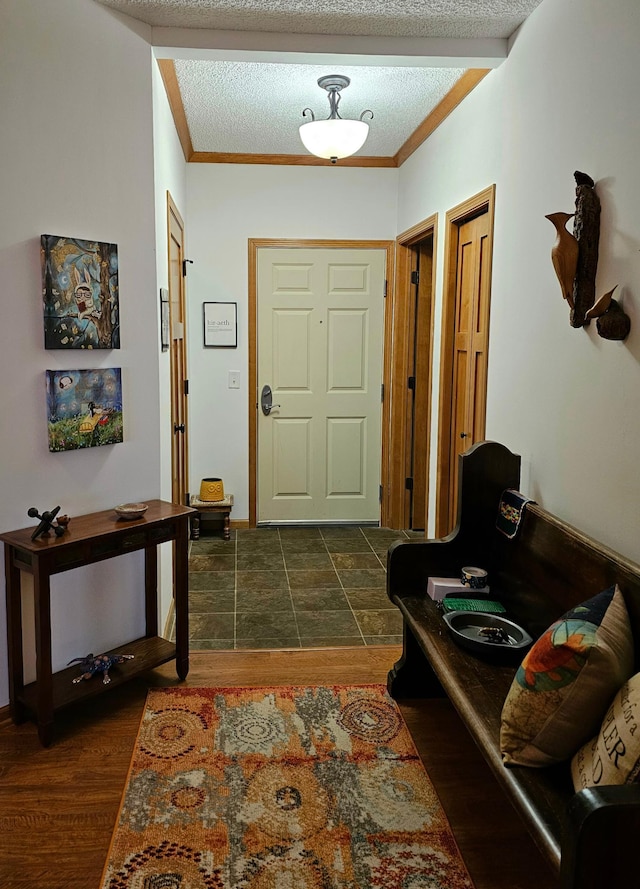 entryway featuring ornamental molding, dark wood-type flooring, and a textured ceiling