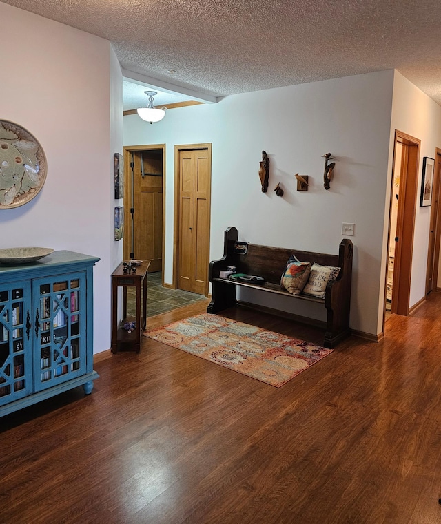 living room featuring dark wood-style flooring, a textured ceiling, and baseboards