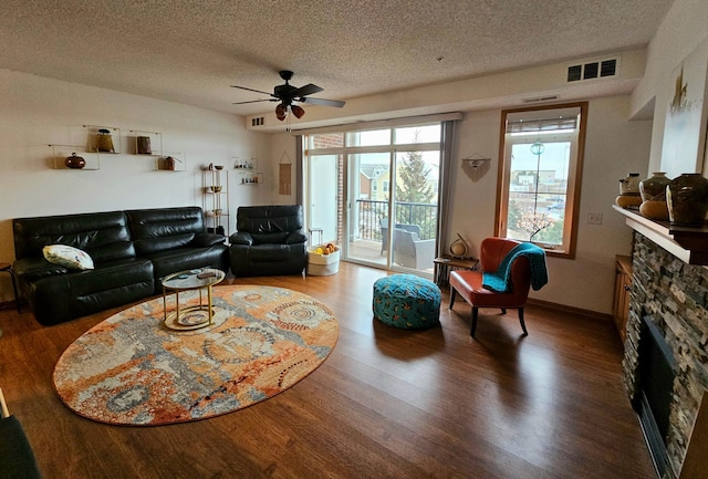 living area with a textured ceiling, a fireplace, visible vents, and wood finished floors