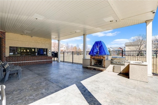 view of patio with fence, grilling area, an outdoor kitchen, and an outdoor fireplace