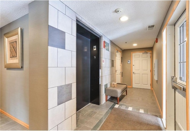 hall with baseboards, visible vents, and a textured ceiling