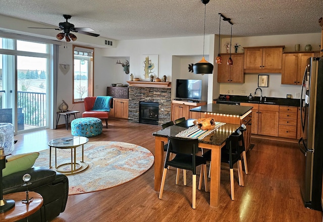 14587 Florissant Path Unit 225, Apple Valley, MN 55124 - dining space featuring a ceiling fan, dark wood-style floors, a textured ceiling, and a stone fireplace