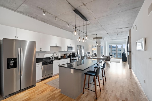 kitchen featuring pendant lighting, light hardwood / wood-style flooring, white cabinetry, stainless steel appliances, and a kitchen island