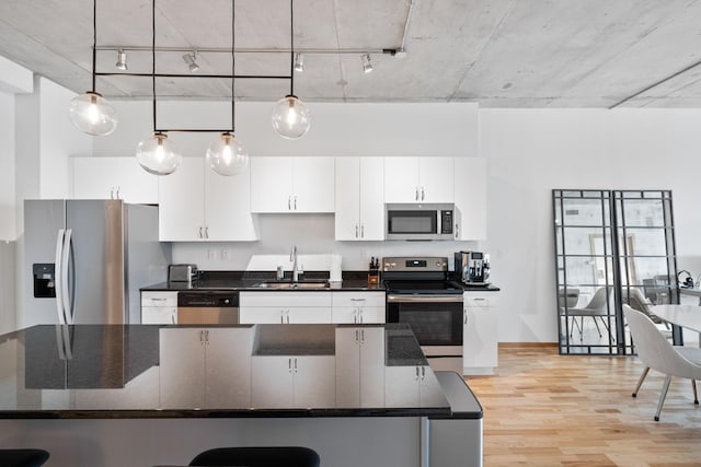 kitchen featuring decorative light fixtures, sink, white cabinets, dark stone counters, and stainless steel appliances