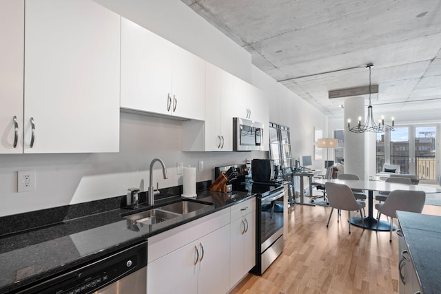 kitchen featuring white cabinetry, appliances with stainless steel finishes, decorative light fixtures, and sink