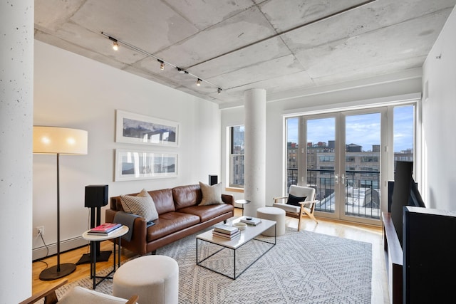 living room featuring a baseboard heating unit, rail lighting, hardwood / wood-style floors, and french doors