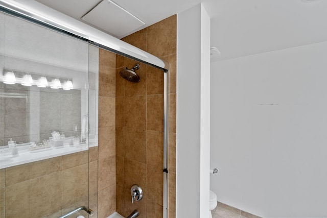 bathroom featuring tile patterned flooring, shower / bath combination with glass door, and toilet