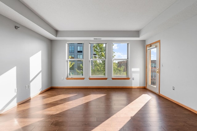 unfurnished room with dark hardwood / wood-style flooring and a textured ceiling