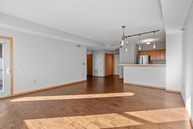 unfurnished living room with rail lighting and dark hardwood / wood-style floors